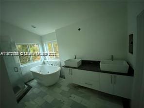 bathroom featuring tile floors, lofted ceiling, and a bath to relax in