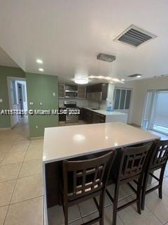 kitchen featuring a kitchen bar and light tile flooring