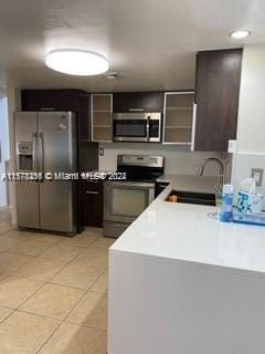 kitchen featuring dark brown cabinets, sink, appliances with stainless steel finishes, and light tile floors