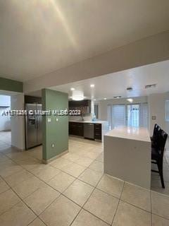 kitchen with refrigerator, green cabinets, and light tile flooring