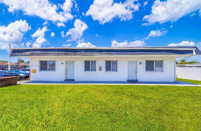 view of front of property featuring stucco siding, fence, and a front yard