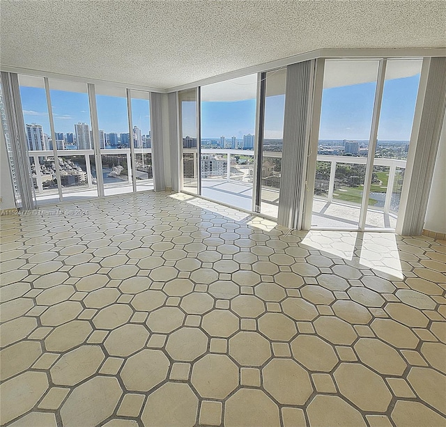 unfurnished room featuring a wall of windows, tile floors, and a textured ceiling