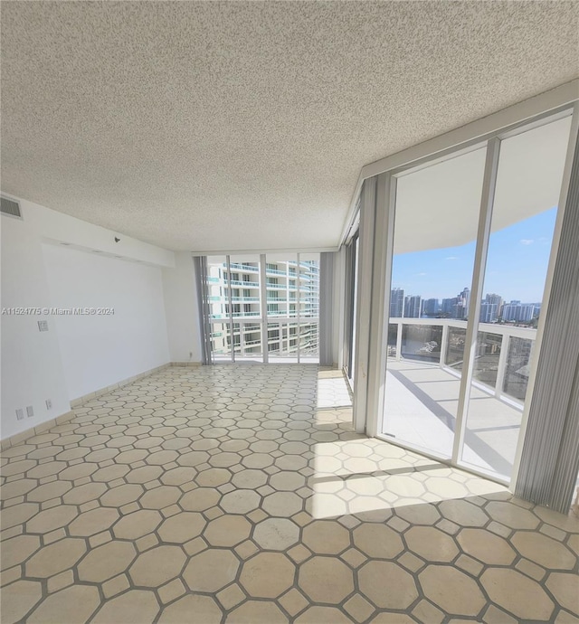 unfurnished room featuring tile flooring, expansive windows, and a textured ceiling