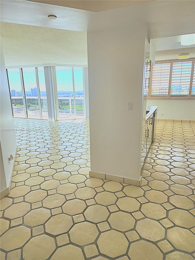 hallway with a healthy amount of sunlight, a textured ceiling, and light tile flooring