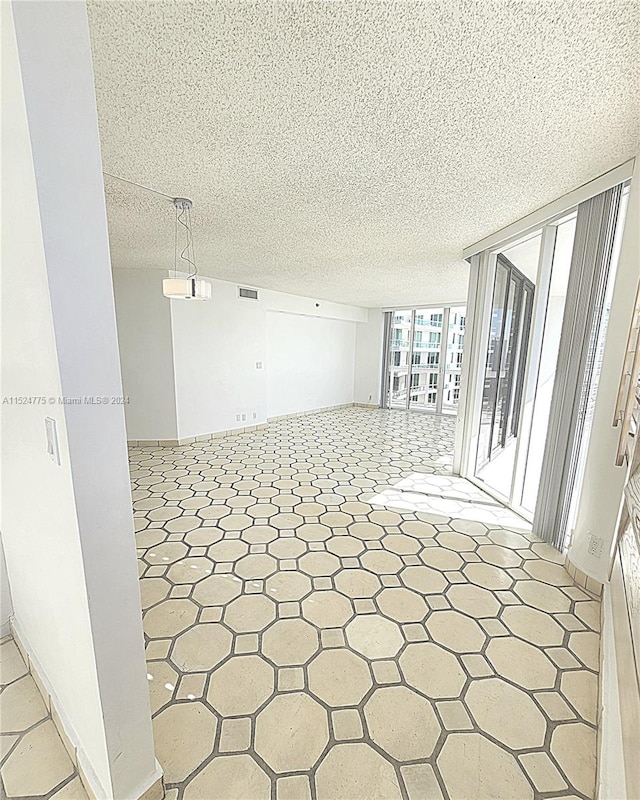 unfurnished room with a textured ceiling and tile flooring