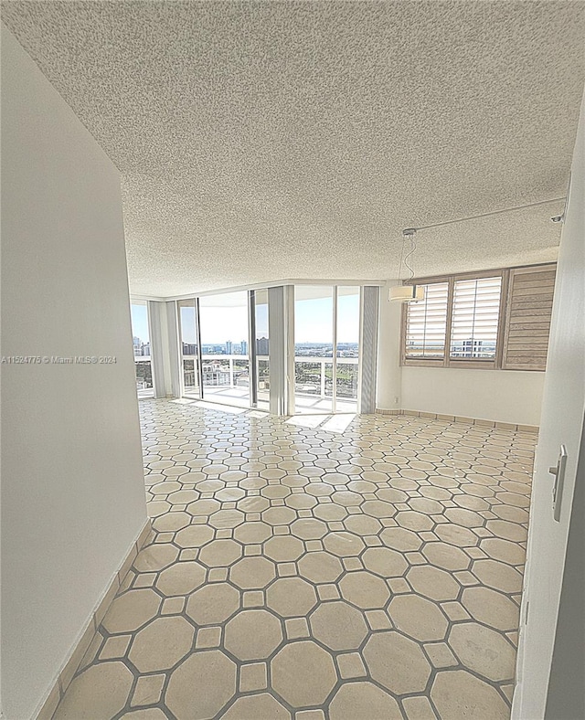 tiled empty room with floor to ceiling windows and a textured ceiling