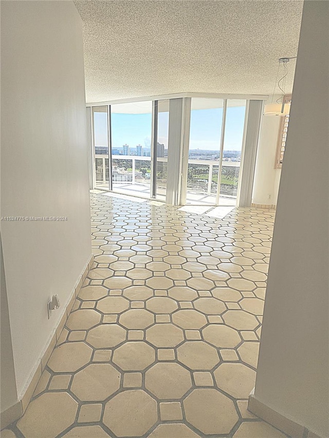 hall with floor to ceiling windows, a textured ceiling, and light tile floors