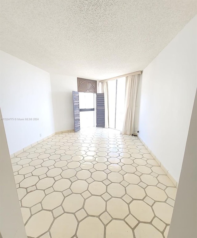 unfurnished room featuring tile flooring and a textured ceiling