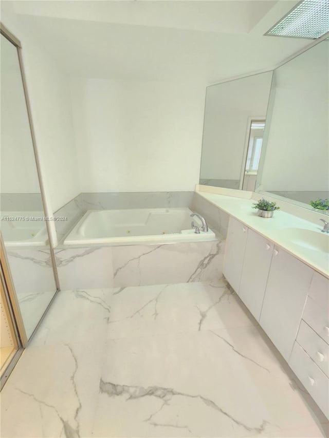 bathroom featuring tile flooring, a relaxing tiled bath, and vanity