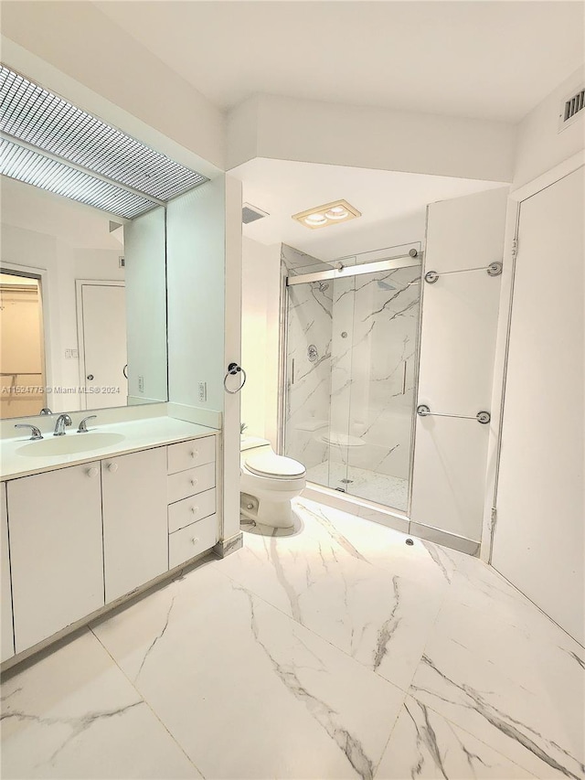 bathroom with a shower with shower door, vanity, tile floors, and toilet