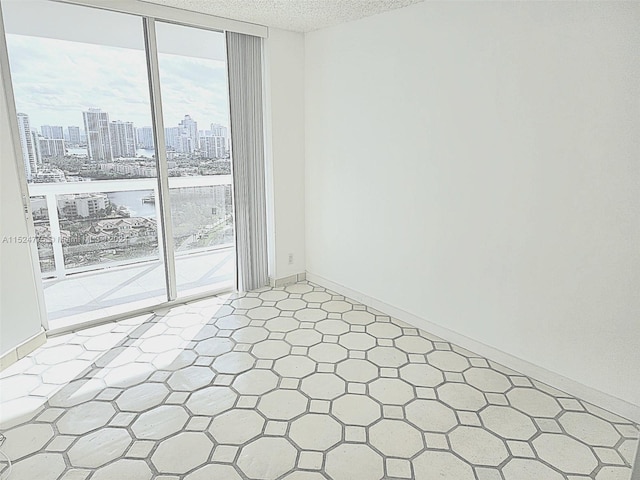 tiled empty room featuring a wall of windows, a textured ceiling, and a wealth of natural light