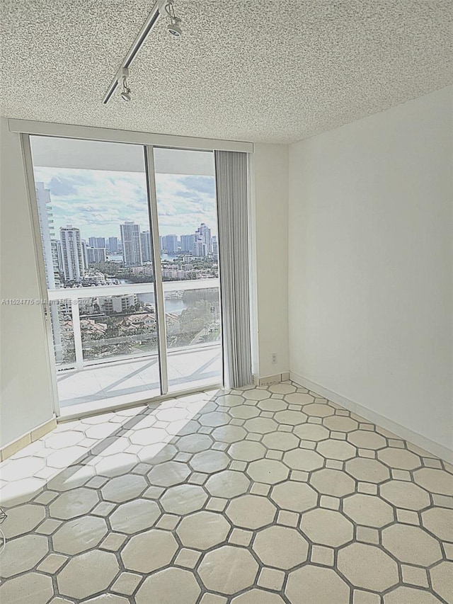 tiled empty room with a textured ceiling and track lighting