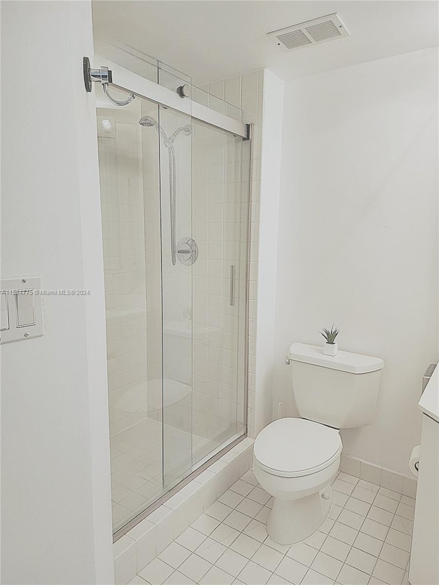 bathroom featuring tile flooring, vanity, an enclosed shower, and toilet