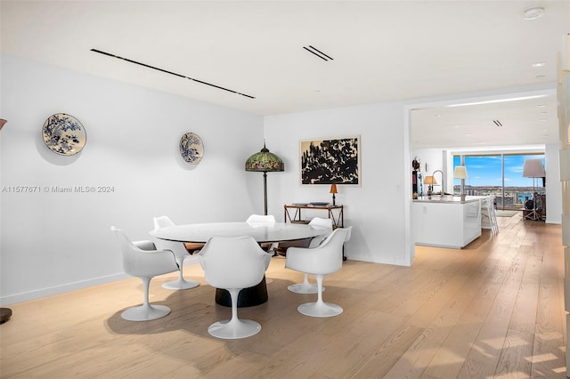 dining area featuring sink, light hardwood / wood-style floors, and expansive windows