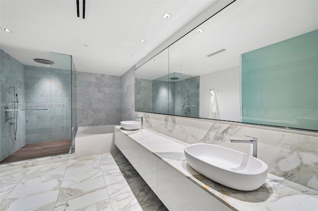 bathroom featuring tile flooring, sink, tile walls, and a bath