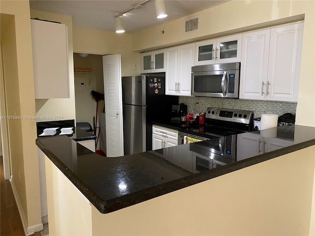 kitchen featuring white cabinetry, kitchen peninsula, appliances with stainless steel finishes, and tasteful backsplash