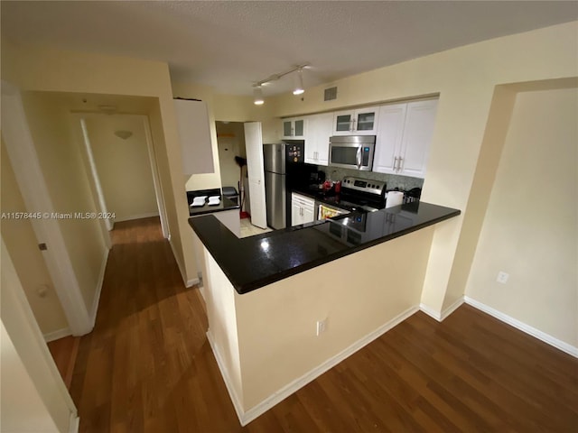 kitchen featuring dark hardwood / wood-style floors, white cabinets, kitchen peninsula, stainless steel appliances, and backsplash