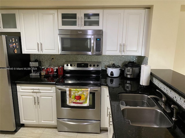 kitchen featuring white cabinets, backsplash, light tile patterned floors, stainless steel appliances, and sink