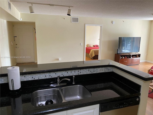 kitchen featuring light wood-type flooring, dishwasher, a textured ceiling, sink, and white cabinetry