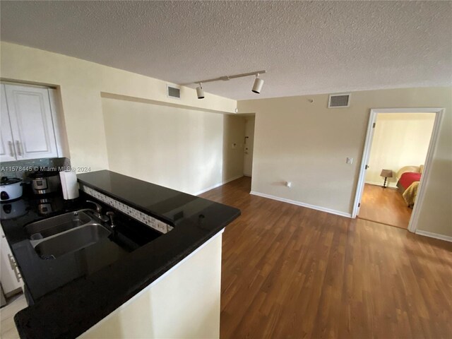 kitchen with a textured ceiling, wood-type flooring, and white cabinets