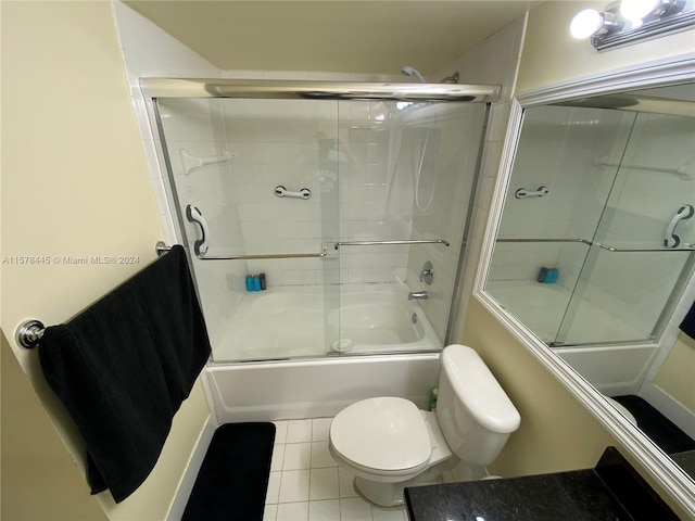 bathroom featuring combined bath / shower with glass door, tile patterned flooring, and toilet