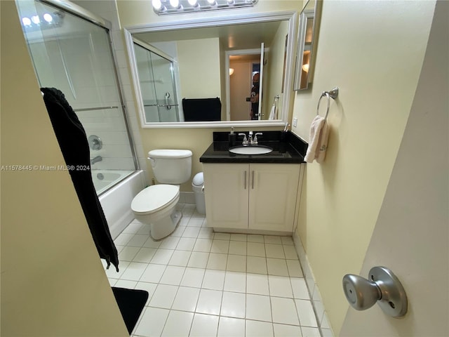 full bathroom with tile patterned floors, bath / shower combo with glass door, vanity, and toilet