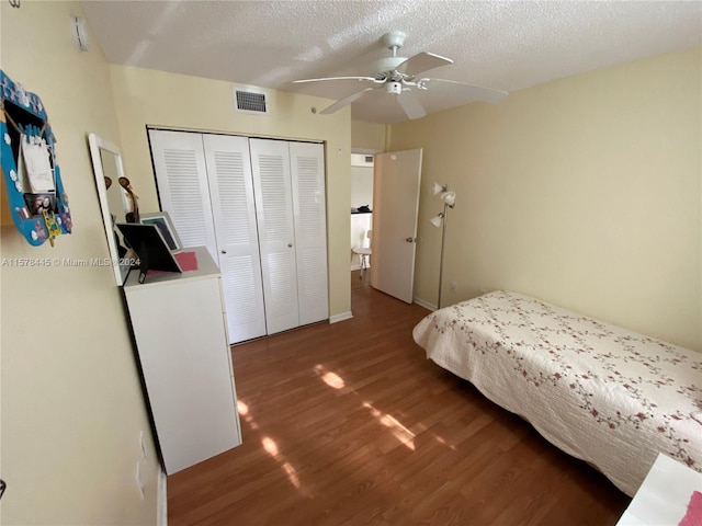 bedroom with dark wood-type flooring, a closet, ceiling fan, and a textured ceiling