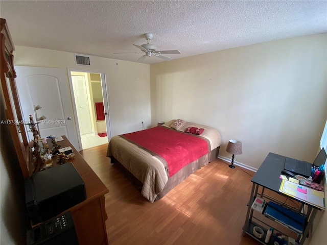 bedroom with ceiling fan, hardwood / wood-style flooring, and a textured ceiling