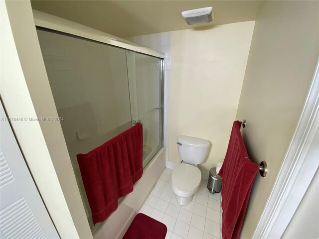 bathroom with tile patterned flooring, enclosed tub / shower combo, and toilet