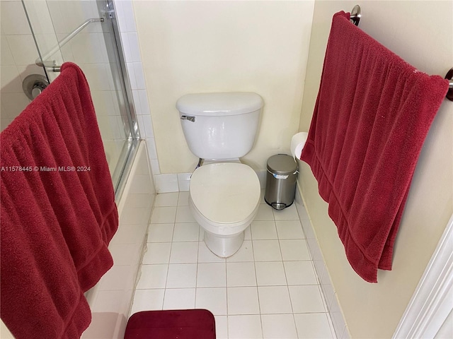 bathroom with bath / shower combo with glass door, toilet, and tile patterned floors