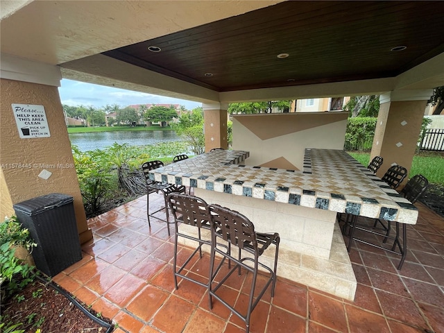 view of patio featuring a water view and exterior bar