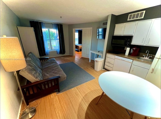 living room featuring a textured ceiling, sink, and light hardwood / wood-style floors