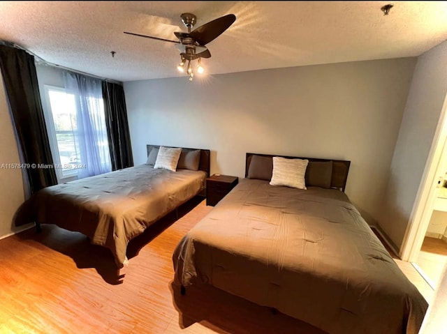 bedroom with light hardwood / wood-style flooring, connected bathroom, ceiling fan, and a textured ceiling