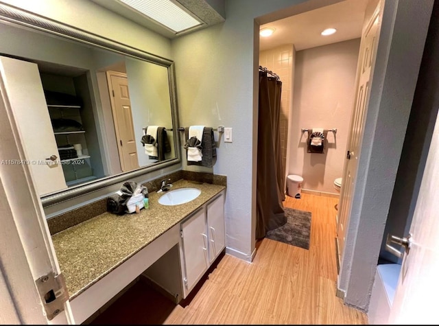 bathroom featuring toilet, vanity with extensive cabinet space, and hardwood / wood-style flooring