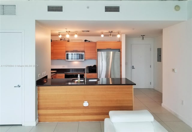 kitchen with sink, kitchen peninsula, light tile floors, and appliances with stainless steel finishes