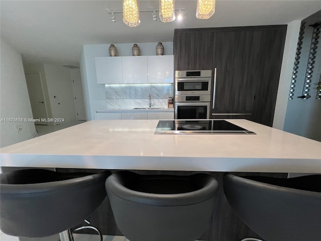 kitchen with double oven, a center island, black electric cooktop, and sink