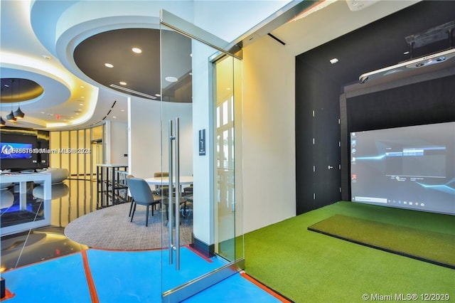 game room featuring a tray ceiling and golf simulator