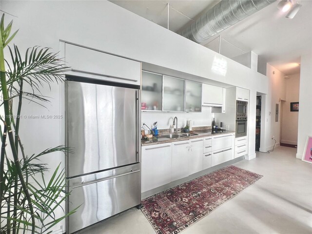 kitchen with white cabinetry, sink, a high ceiling, and appliances with stainless steel finishes