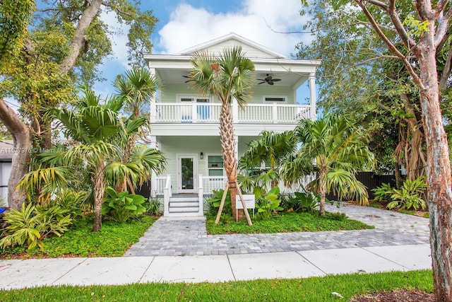 raised beach house with covered porch, ceiling fan, and a balcony