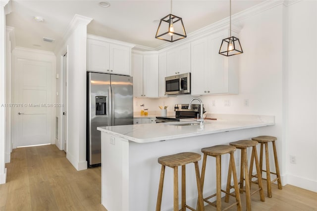 kitchen with white cabinets, light wood-type flooring, ornamental molding, kitchen peninsula, and appliances with stainless steel finishes