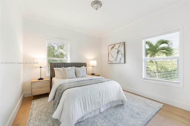 bedroom featuring ornamental molding, multiple windows, and hardwood / wood-style flooring