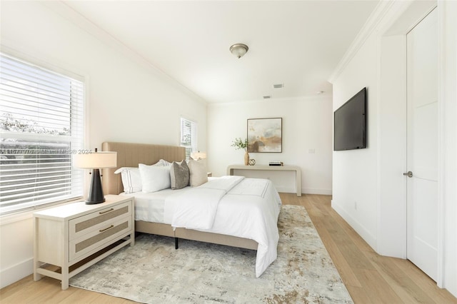 bedroom with light hardwood / wood-style floors and ornamental molding