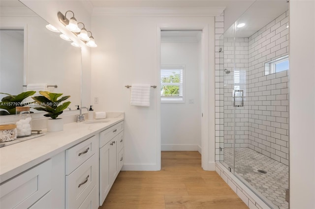 bathroom with wood-type flooring, vanity, crown molding, and a shower with shower door