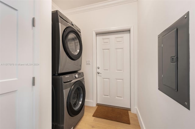 washroom featuring ornamental molding, stacked washer and clothes dryer, and light wood-type flooring