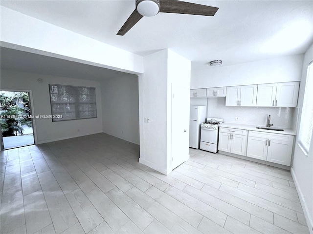 kitchen featuring light hardwood / wood-style floors, ceiling fan, white cabinets, sink, and white appliances