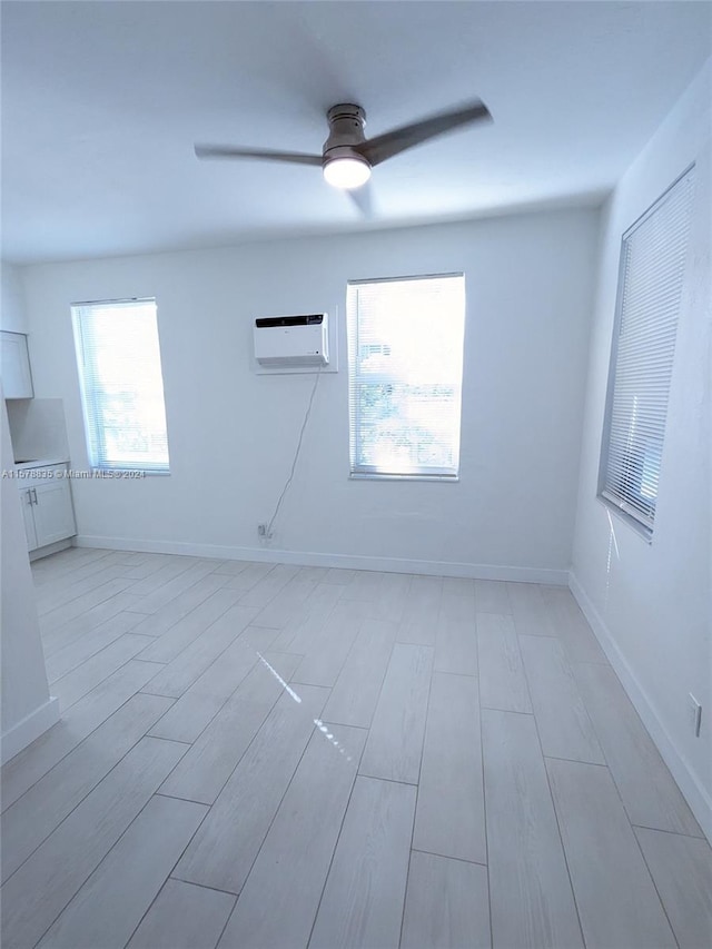 empty room featuring a wall unit AC, ceiling fan, and light hardwood / wood-style flooring