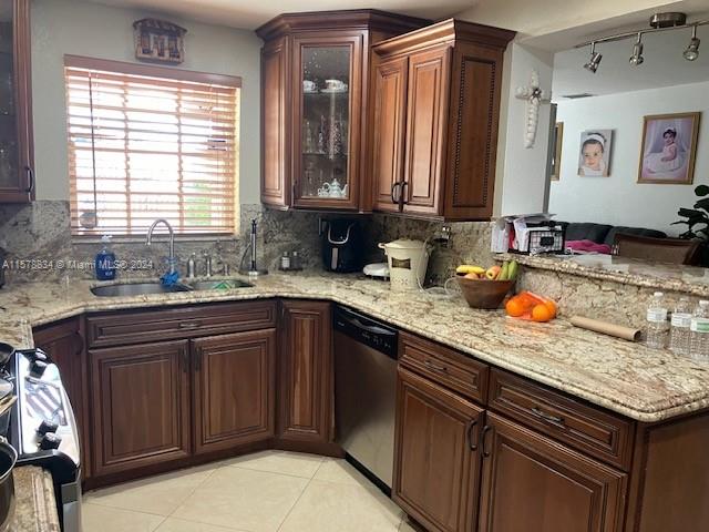 kitchen with light tile patterned floors, sink, decorative backsplash, stainless steel dishwasher, and range