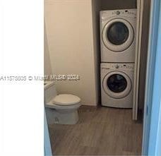 washroom with hardwood / wood-style floors and stacked washer and clothes dryer