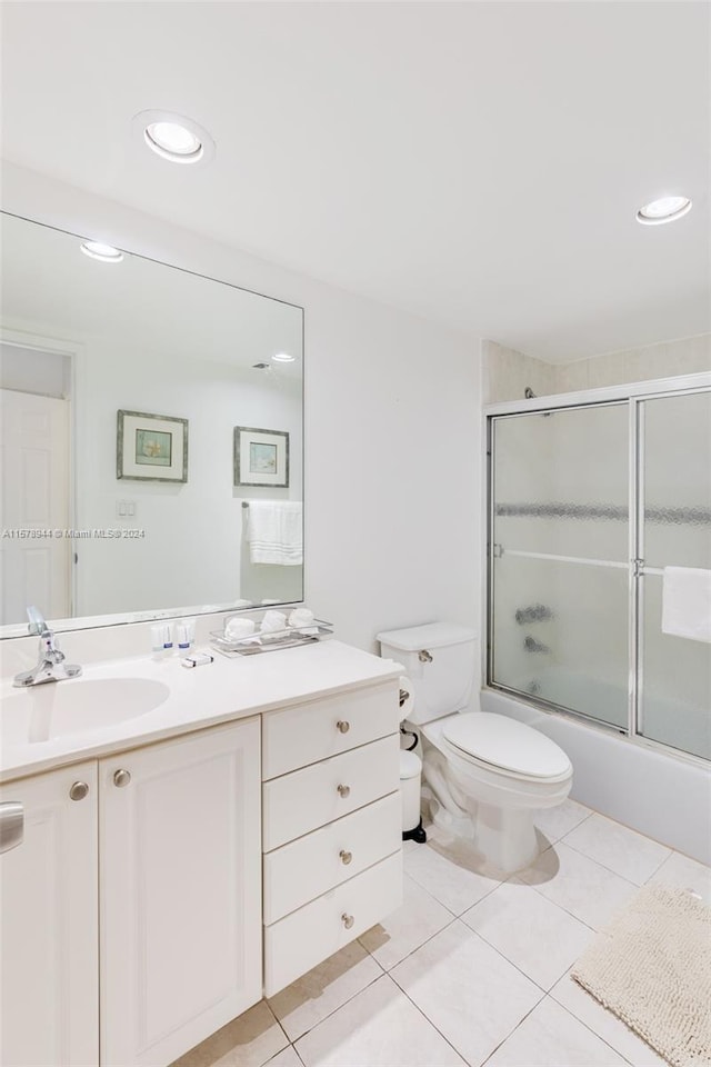 full bathroom with combined bath / shower with glass door, vanity, toilet, and tile patterned flooring