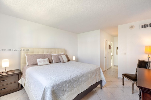 bedroom with light tile patterned floors, a textured ceiling, and a closet